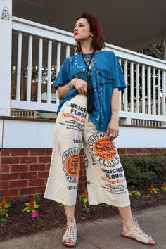 a woman standing on the sidewalk with her hands in her pockets and holding an orange frisbee