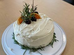 a white cake with oranges and rosemary on top