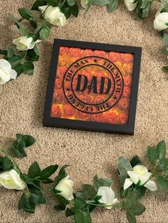 an orange and black box with the word dad on it surrounded by white rose petals