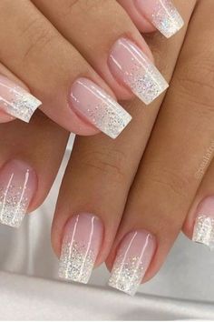 two hands with white and pink nail polishes on their nails, one is holding the other