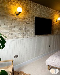 a bedroom with brick walls and white paneling on the wall, along with a flat screen tv