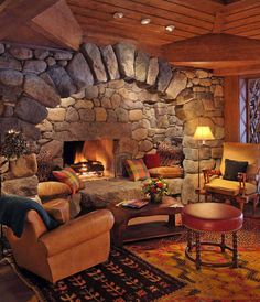 a living room filled with furniture and a fire place next to a stone fireplace covered in logs