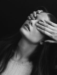 a black and white photo of a woman covering her eyes