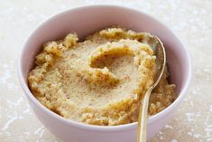 a white bowl filled with oatmeal on top of a table next to a spoon