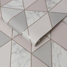 a white and grey wallpaper with geometric design on it's side, next to a roll of tape