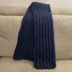 a blue knitted scarf sitting on top of a couch