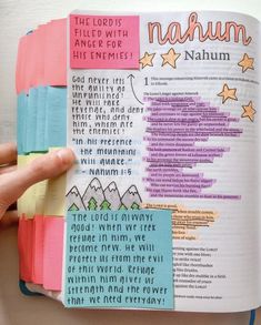 an open bible with colorful sticky notes on the page and hand holding it in front of them