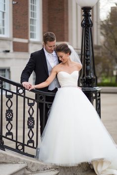 a bride and groom standing on the steps of a building in front of a lamp post