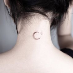 a woman's back neck with a small crescent tattoo on the left side of her neck