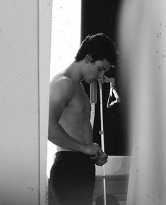 a shirtless man standing in front of a mirror holding a pair of skis