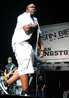 a man standing on top of a stage while holding a microphone in his right hand