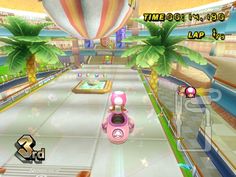 the wii game mario kart is going down the road with palm trees and hot air balloons in the background