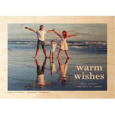 a man and two children are standing on the beach with their arms in the air