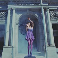 a woman standing on top of a statue in front of a building