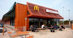 a mcdonald's restaurant with people sitting at tables outside