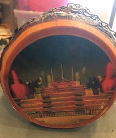 an ornate wooden box with pictures on it's lid and chain around the edges