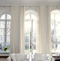 a living room with white furniture and large windows