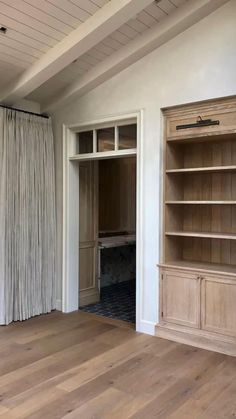 an empty living room with wood flooring and open bookcases on the wall