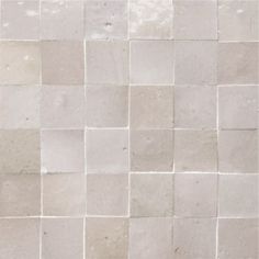 a white tile wall that has been made up of several different sized and shaped tiles