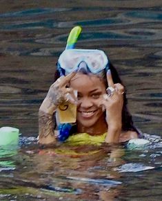 a woman in the water wearing a mask and holding a cell phone to her ear