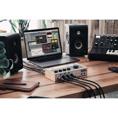 a laptop computer sitting on top of a wooden desk next to speakers and other electronic equipment