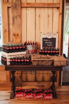 a wooden table topped with lots of bottles of coca - cola next to a sign