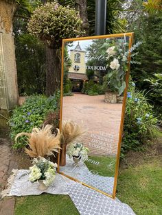 a mirror sitting on top of a grass covered ground next to a flower pot filled with flowers