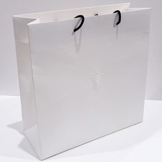 a white paper bag with black handles on a table