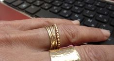 a person's hand with two gold rings on their fingers next to a keyboard