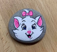 a painted rock with a cartoon cat on it's face and a bow in its hair