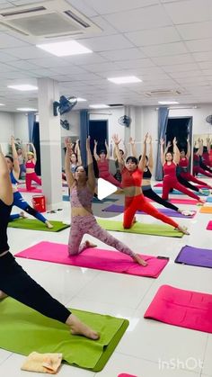 a group of people doing yoga in a room with their arms up and legs crossed