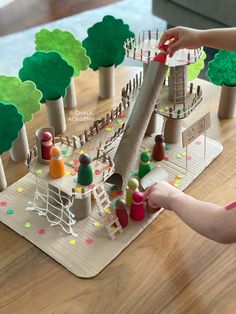 a child is playing with a wooden toy set on a table in front of trees