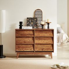 a wooden dresser sitting on top of a hard wood floor next to a white wall