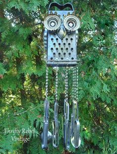 an owl made out of forks and spoons hanging from a tree