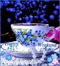 a tea cup and saucer on a table with blue flowers in the background that says happy weekend