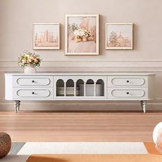 a living room with white furniture and pictures on the wall above it's console table