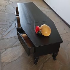 a black desk with two drawers and a vase on top