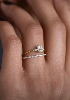 a woman's hand with a diamond ring on top of her finger and an engagement band