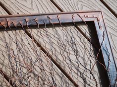 a close up of a metal frame on a wooden wall with barbed wire attached to it