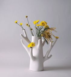 a white vase filled with yellow flowers on top of a table