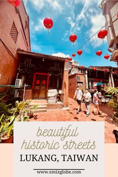 two people walking in front of a building with red lanterns hanging from the roof and below