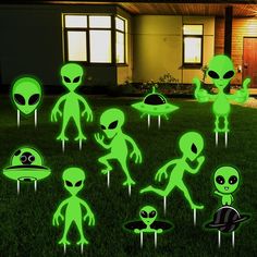 green alien lawn decorations in front of a house at night with the lights turned on