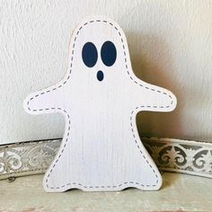 a wooden cut out of a ghost on a shelf