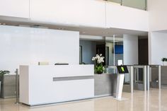 an office lobby with marble counter tops and planters on either side of the reception desk