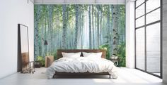 a bedroom with a bed, mirror and wallpaper that has trees painted on it