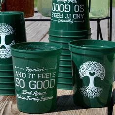 green plastic cups with trees on them sitting on a wooden table next to each other