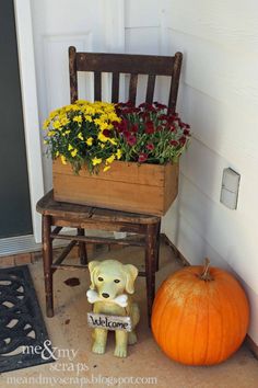 a wooden chair sitting next to a planter filled with flowers and a dog figurine