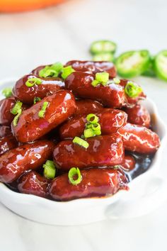 a white bowl filled with hot dogs covered in sauce