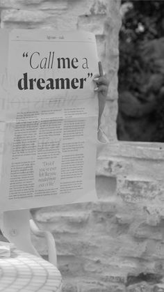 a person sitting in a chair holding up a sign that says call me a dream