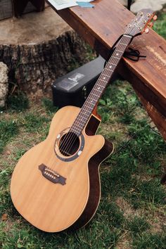 an acoustic guitar sitting on top of a wooden bench